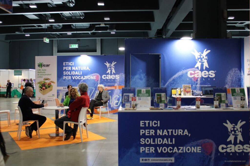 Lo stand del Consorzio CAES alla fiera Fa’ la Cosa Giusta 2023, con materiali informativi su mutualità, finanza etica ed economia solidale