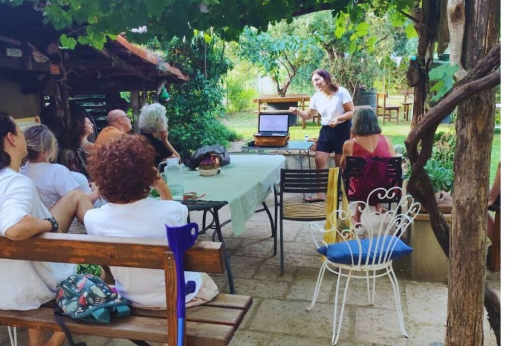 Partecipanti alla vacanza olistica Nonsolomare di Tra Terra e Cielo durante una conferenza all’aperto, immersi nel verde.