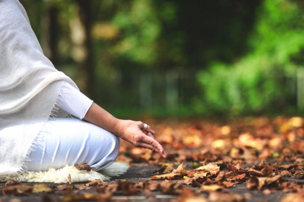Persona in meditazione nel bosco durante il digital detox di Autosufficienza