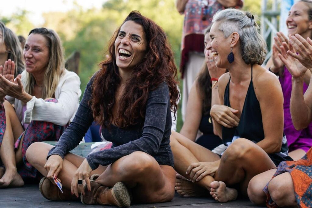 Federica Clemente al Festival della Sacralità Femminile, sorridente in cerchio con altre partecipanti