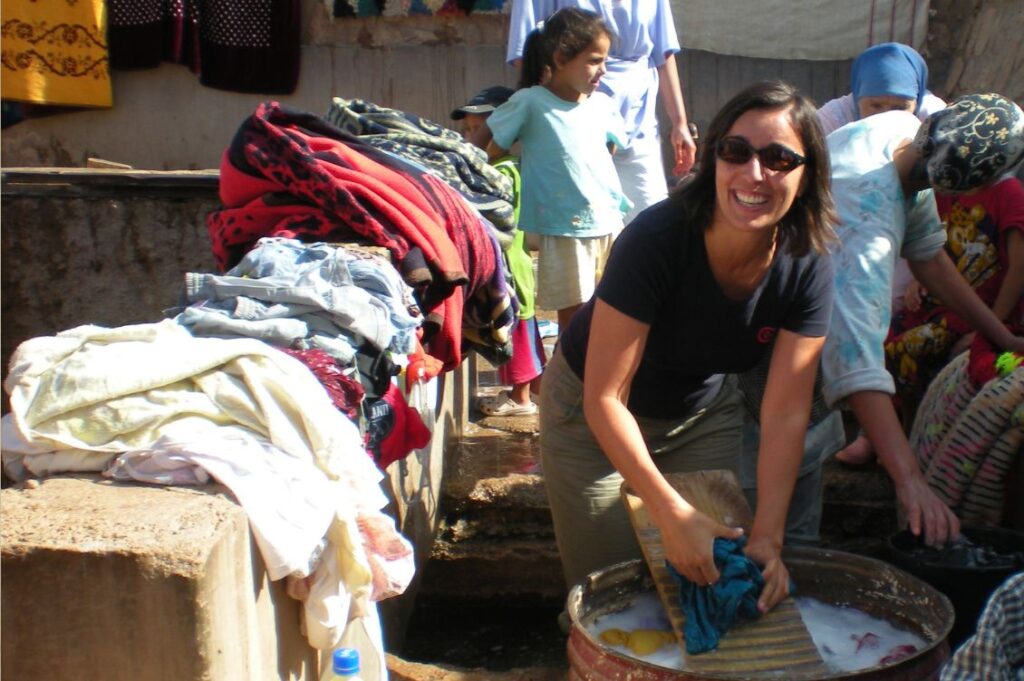 Viaggiatrice che fa il bucato con le donne del villaggio di Tazouta, in Marocco, durante un’esperienza di turismo responsabile.
